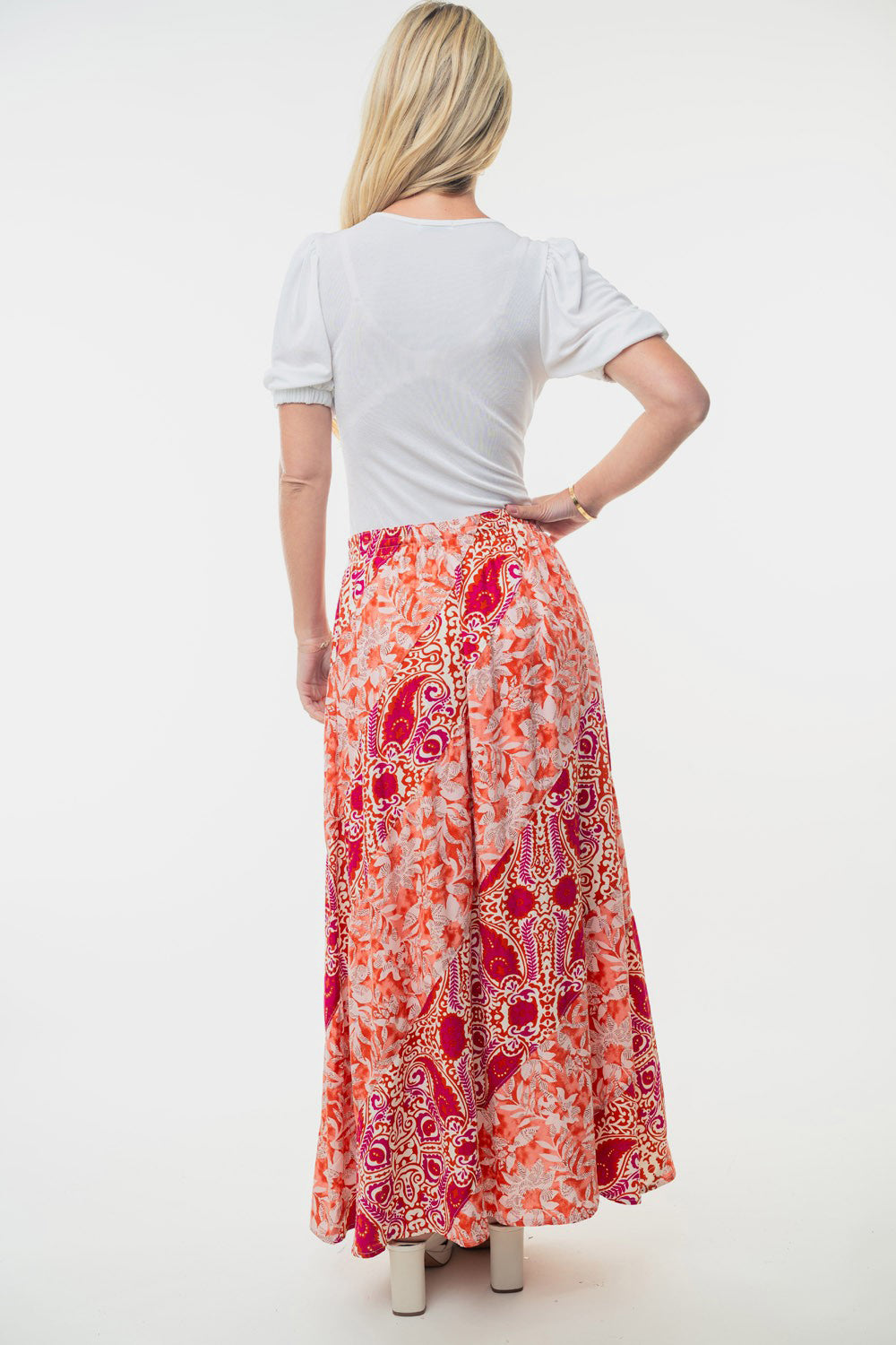 A woman stands posing against a white background, wearing a white short-sleeved blouse paired with the White Birch Full Size High Waisted Floral Woven Skirt, which showcases colorful patterns. The outfit creates a flattering silhouette perfect for any occasion.