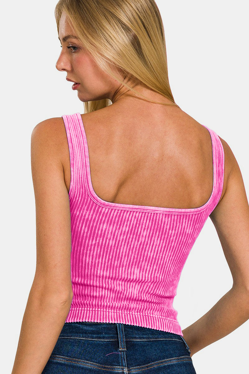 A person wearing the Zenana Washed Ribbed Cropped Bra Padded Tank in a stylish pink stands against a white background, showcasing the comfort of their wardrobe choice.