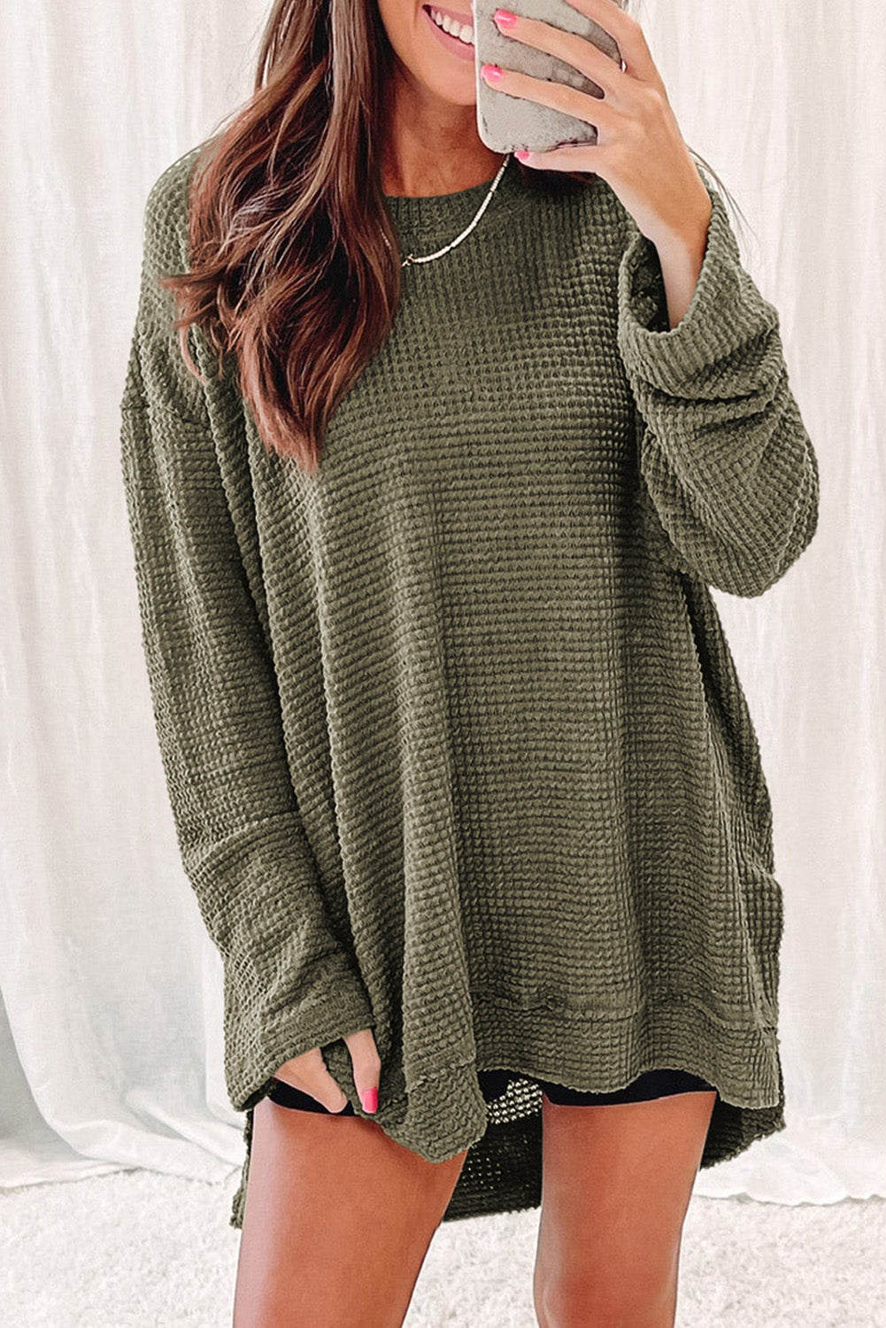 Person wearing a trendy Green Waffle Knit Drop Sleeve High Slits Oversized Top takes a mirror selfie, showcasing the cozy waffle knit texture along with their upper and part of their lower body.