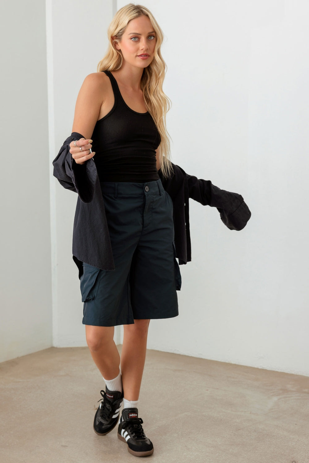 Person wearing a black sleeveless top and Le Lis Navy Cargo Bermuda Shorts with pockets, perfect for a warm-weather wardrobe.