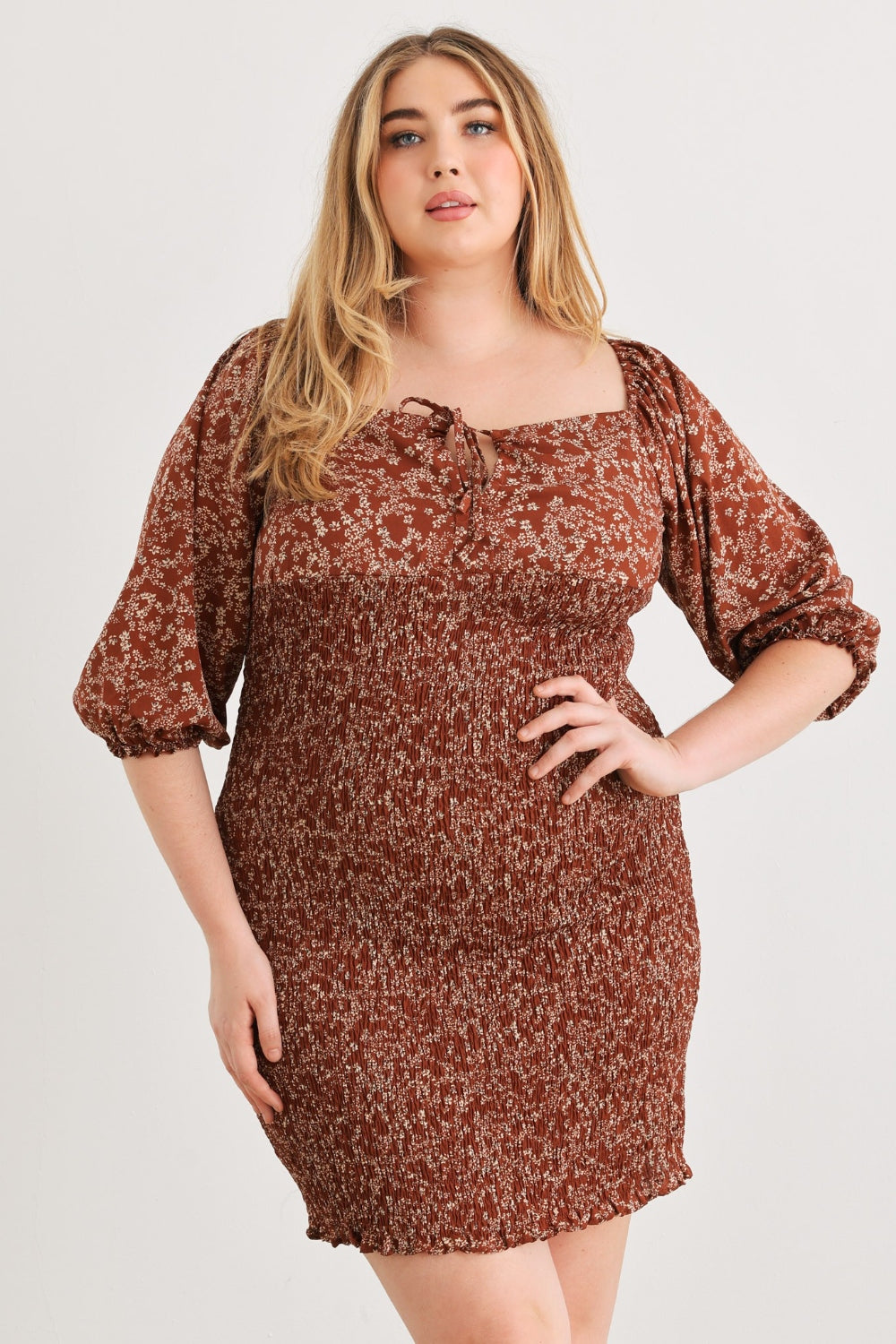 A person poses confidently wearing the Zenobia Plus Size Smocked Printed Square Neck Mini Dress in black and white, paired with black sandals, against a plain white background.