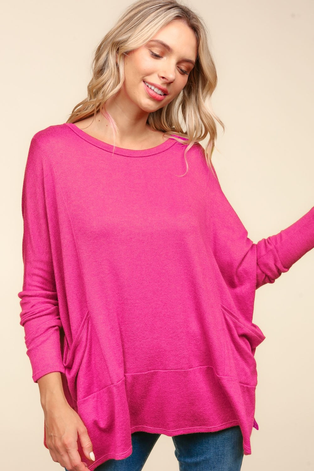 A person wearing a Haptics Dolman Long Sleeve Oversized Knit Top with Pockets in bright pink stands against a plain background.