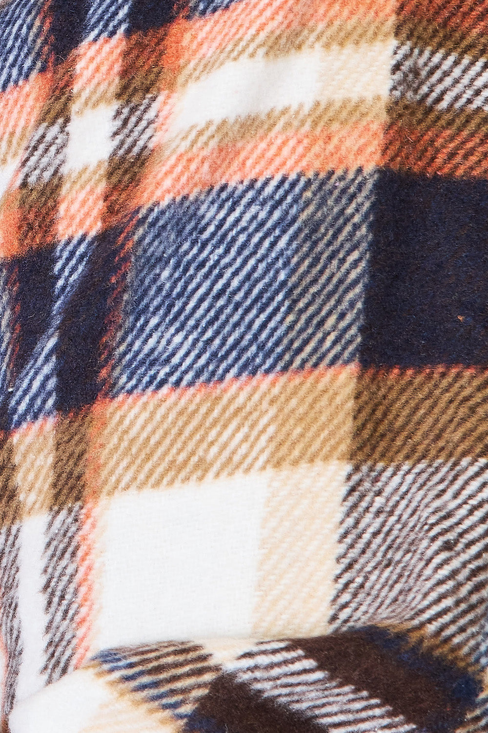 A person with long braided hair wearing the Double Take Plaid Button Front Shirt Jacket with Breast Pockets over a white top and blue jeans stands with a hand in their pocket, posing in an indoor setting. The layering of the jacket adds an effortless touch to the outfit.