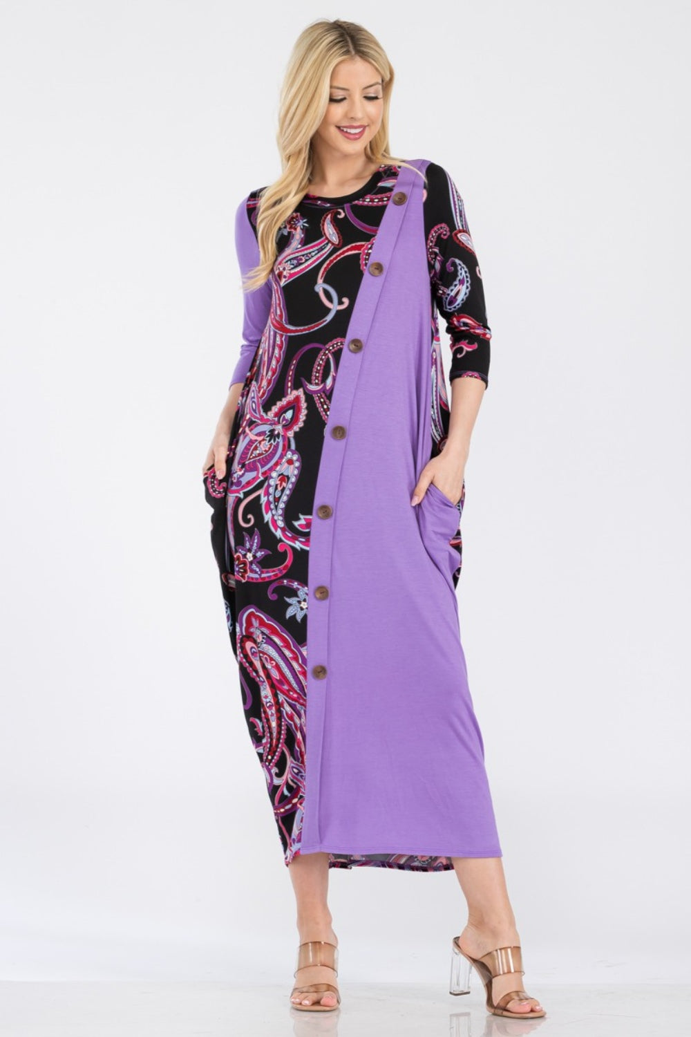 A woman wearing the Celeste Full Size Paisley Contrast Midi Dress with pockets, showcasing a versatile purple and black paisley print, button front detail, and long sleeves.