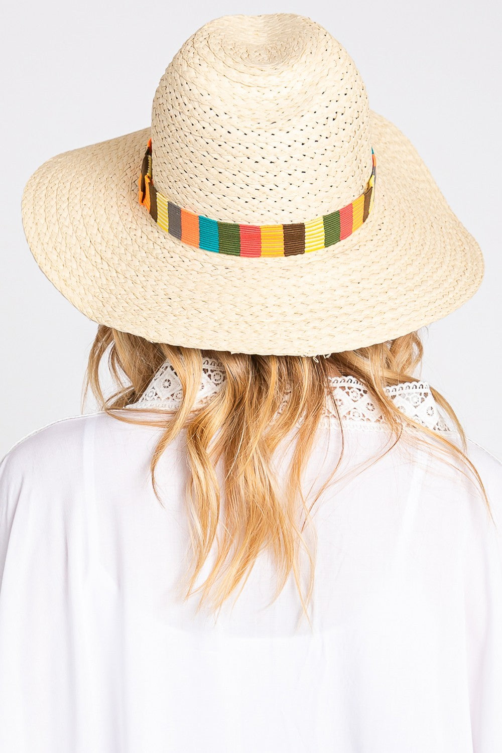 The Fame Contrast Wide Brim Straw Hat, featuring a vibrant multicolor band, is elegantly showcased on a sandy beach background with delicate palm leaf shadows, making it the ideal stylish accessory for sun protection.