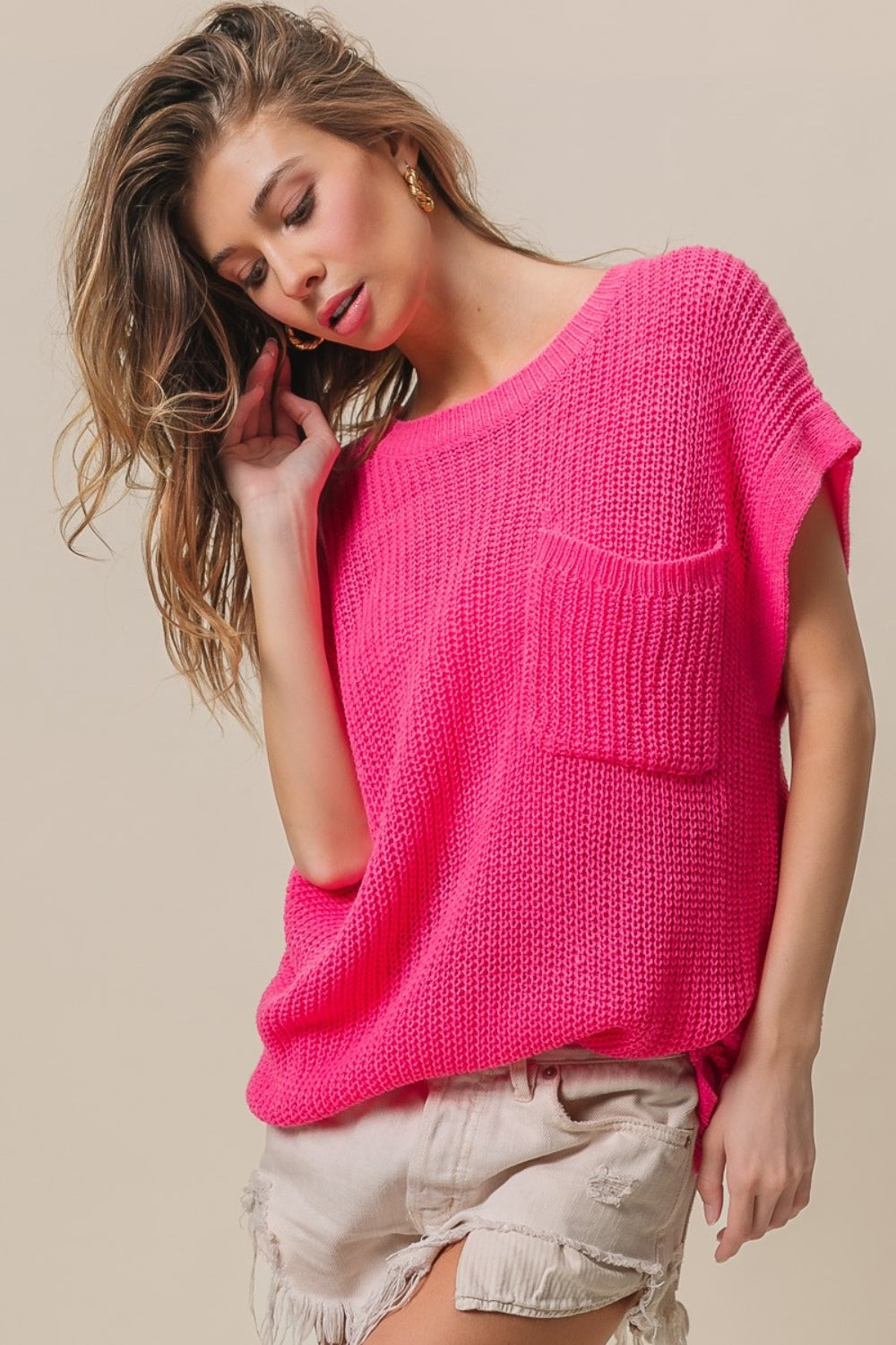 A woman wearing the BiBi Patch Pocket Short Sleeve Sweater, a cozy knit in pink.