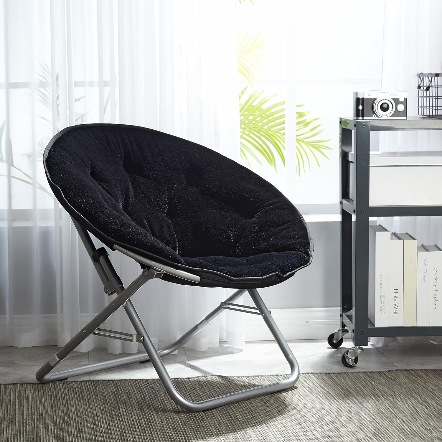 A black, round, collapsible Faux Fur Saucer Chair with a soft cushioned seat and a metallic frame.