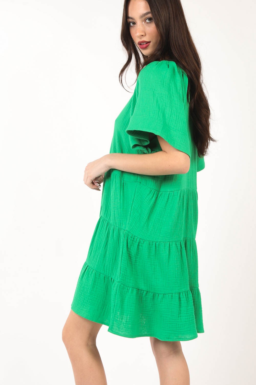 A woman poses against a white background, elegantly showcasing the flattering silhouette of the VERY J Texture V-Neck Ruffled Tiered Dress.