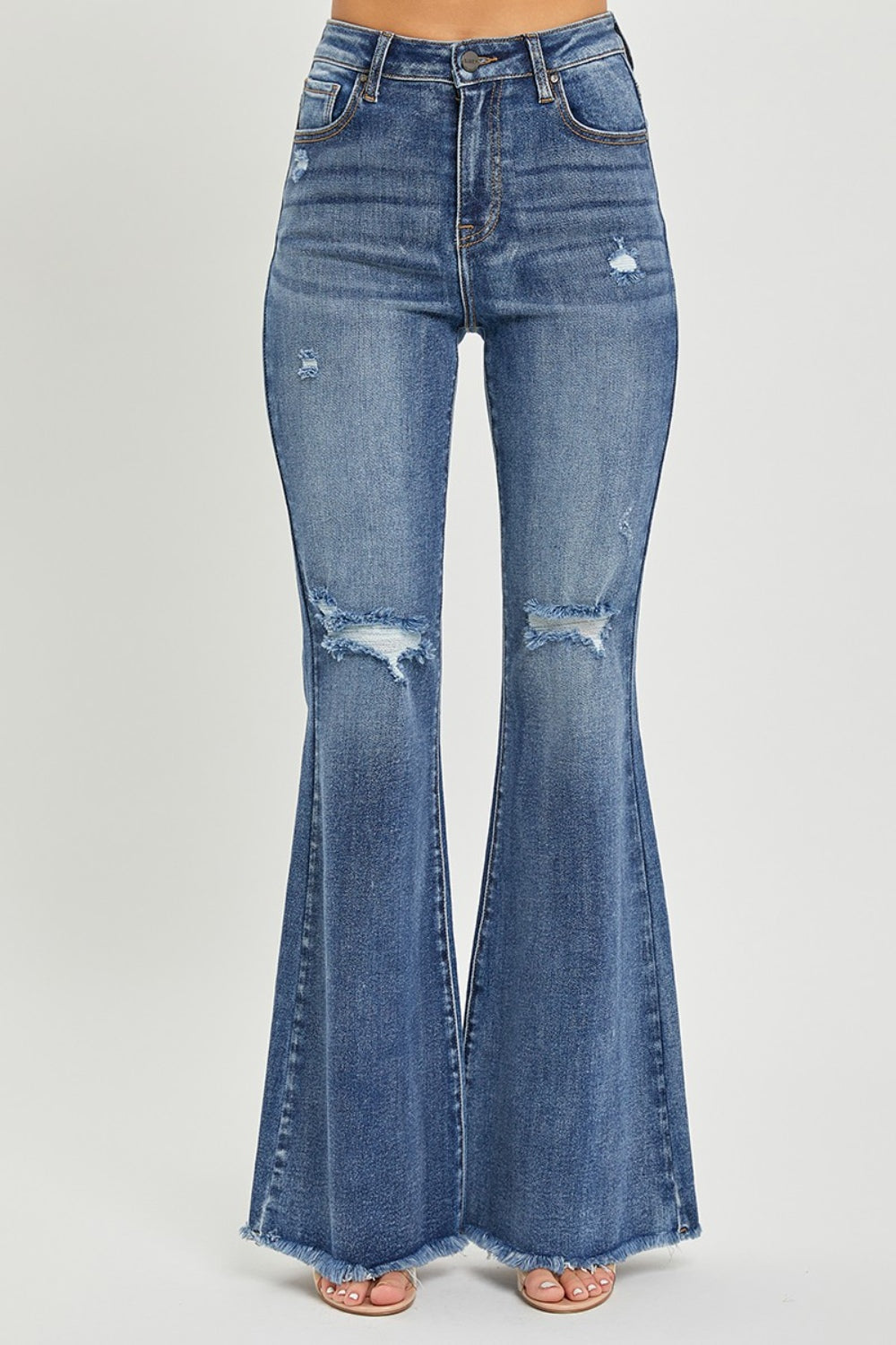 A person is wearing RISEN High Waist Distressed Fare Jeans, characterized by a high-waisted fit with minor rips and frayed hems, standing against a neutral background.