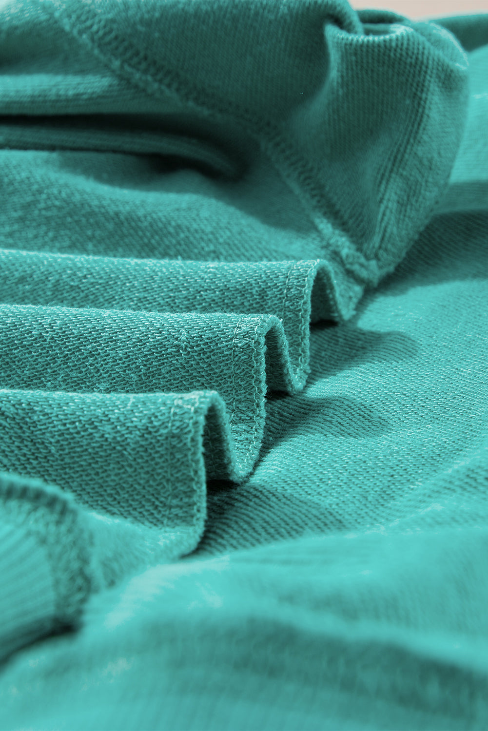 Person with long hair wearing an Aruba Blue Plain Drop Shoulder Crewneck Pullover Sweatshirt and carrying a floral crossbody bag, seen from the back, walking outdoors.