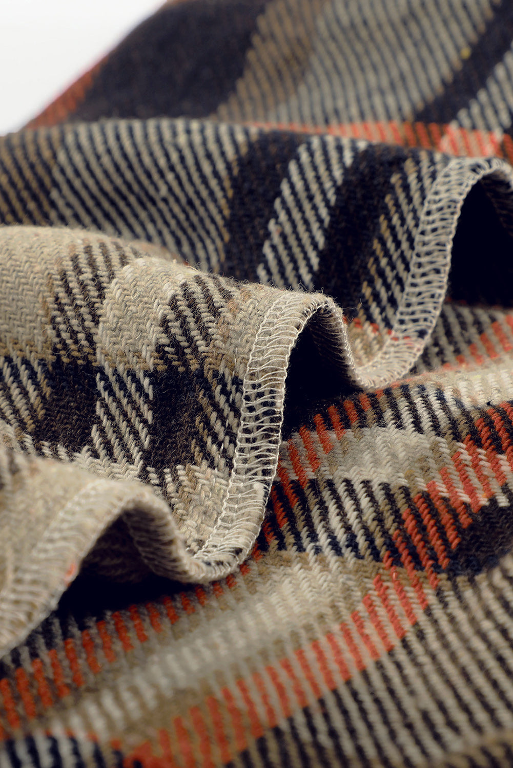 A person wearing a Brown Plaid Button Up Long Sleeve Flannel Shacket layered over a white top with ripped jeans and holding a brown handbag stands against a textured gray wall.