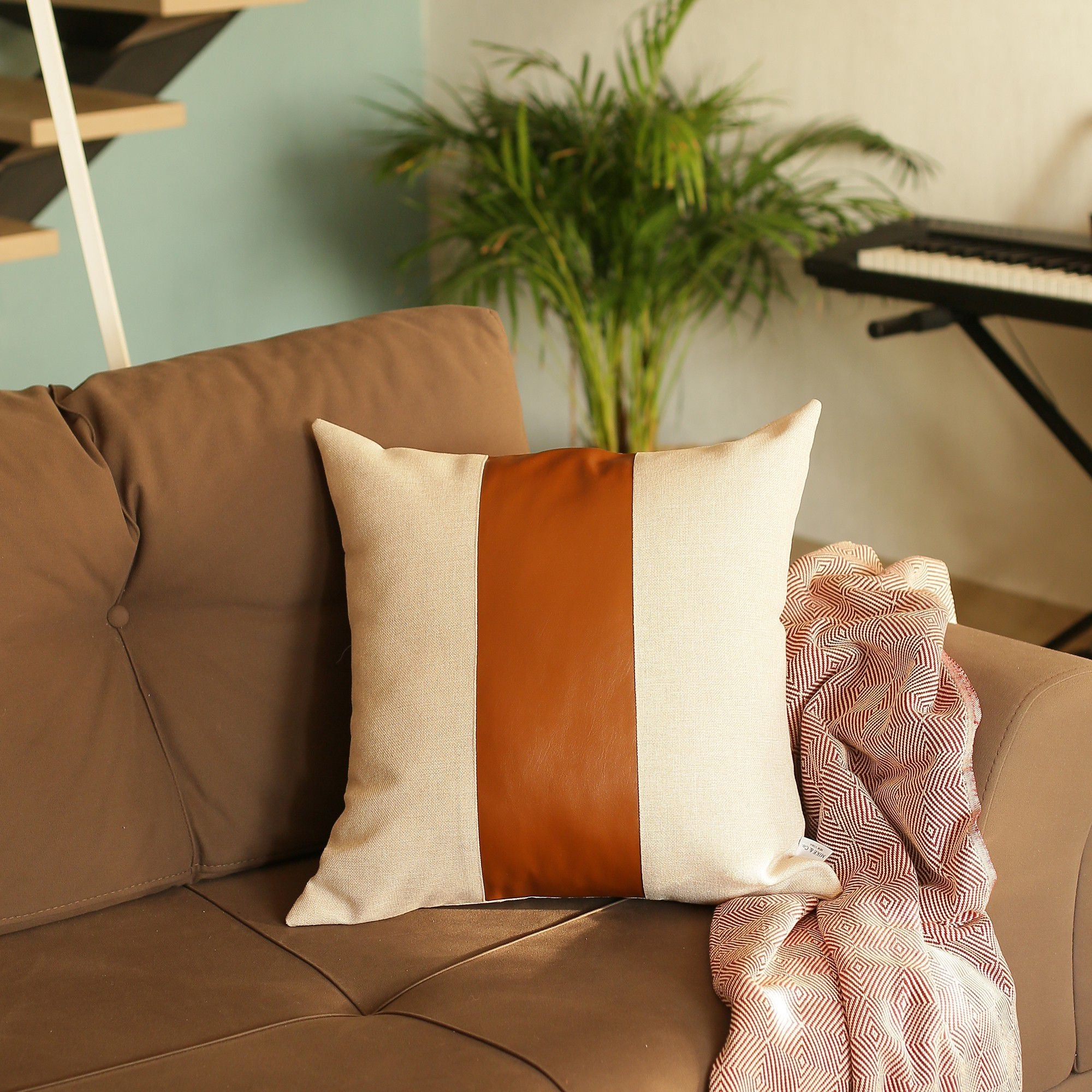 In a well-lit room, a black wire chair is tastefully adorned with a Boho Handcrafted Decorative Single Throw Pillow Cover in beige and brown, featuring vegan faux leather.