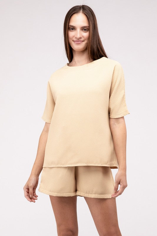 Clad in the Waffle Round Neck Top and Short Set paired with black sunglasses, a person stands against a plain beige background, highlighting the non-stretch polyester fabric.