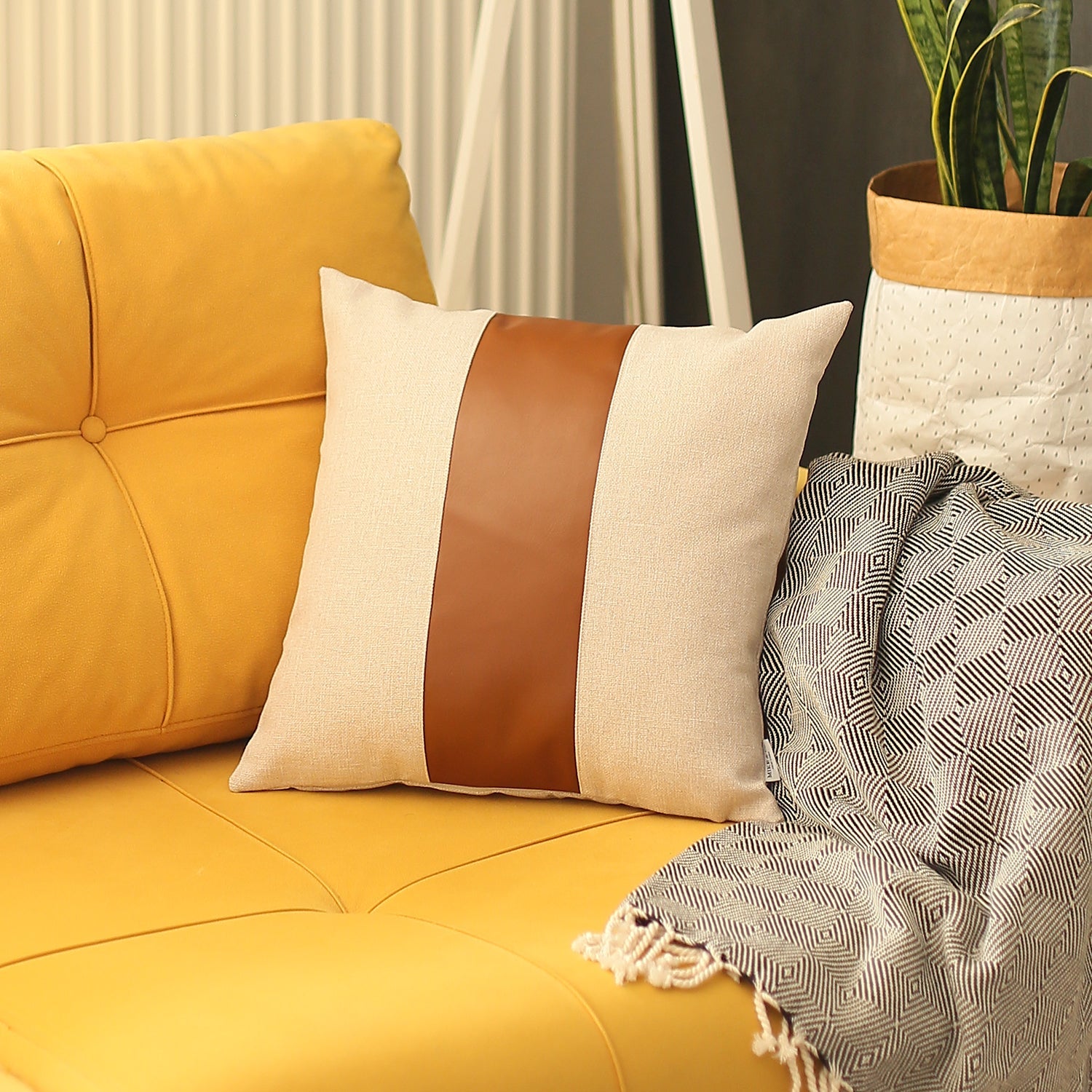 In a well-lit room, a black wire chair is tastefully adorned with a Boho Handcrafted Decorative Single Throw Pillow Cover in beige and brown, featuring vegan faux leather.
