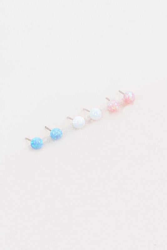 Five Tiny Sphere stud earrings arranged in a line on a pale background.