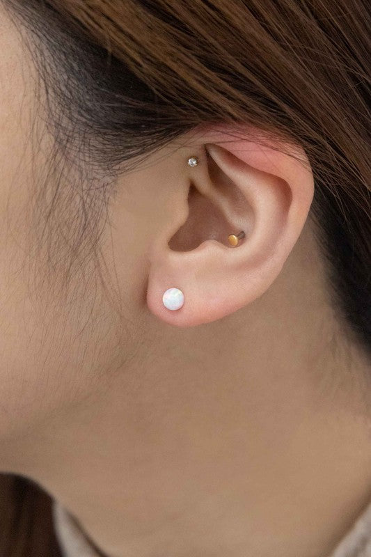 Five Tiny Sphere stud earrings arranged in a line on a pale background.