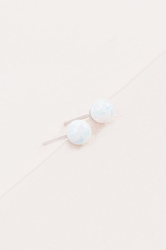 Five Tiny Sphere stud earrings arranged in a line on a pale background.