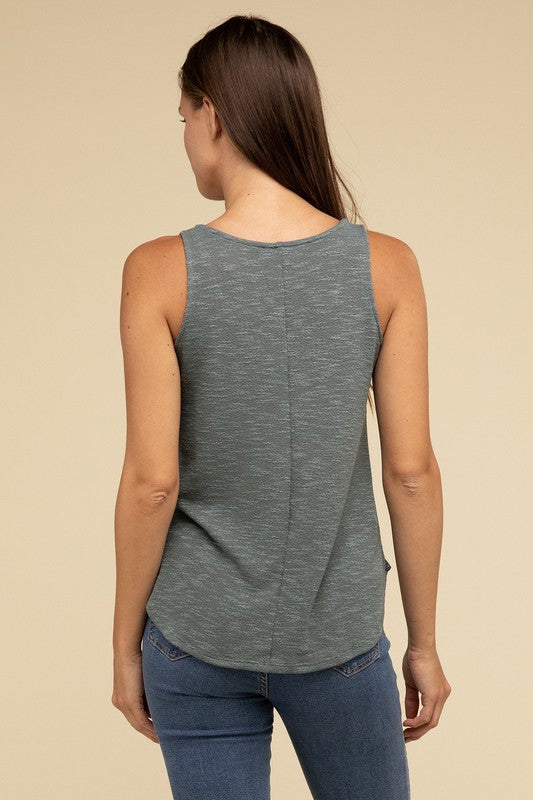 A woman in a stylish and adaptable V Neck Sleeveless Cami Top paired with jeans stands against a beige background. She has long brown hair and maintains a neutral expression.