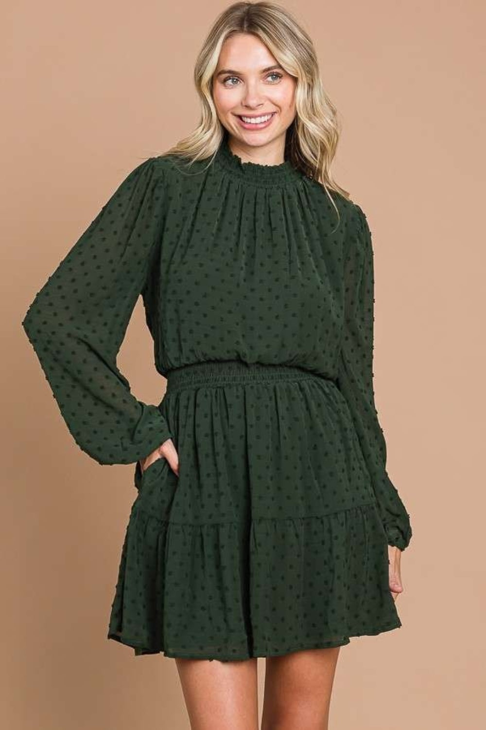 Draped gracefully, a woman wears the Culture Code Swiss Dot Smock Neck Mini Dress with Pockets in green crinkle chiffon.