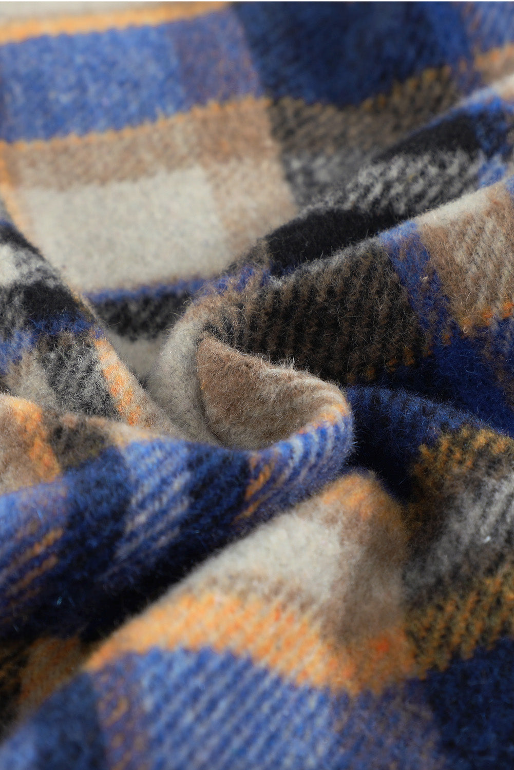 A person wearing a Brown Plaid Button Up Long Sleeve Flannel Shacket layered over a white top with ripped jeans and holding a brown handbag stands against a textured gray wall.