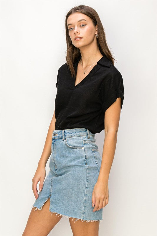 A woman with long hair is wearing the Always a Delight Short Sleeve Linen Top in brown and black pants, standing against a beige background.