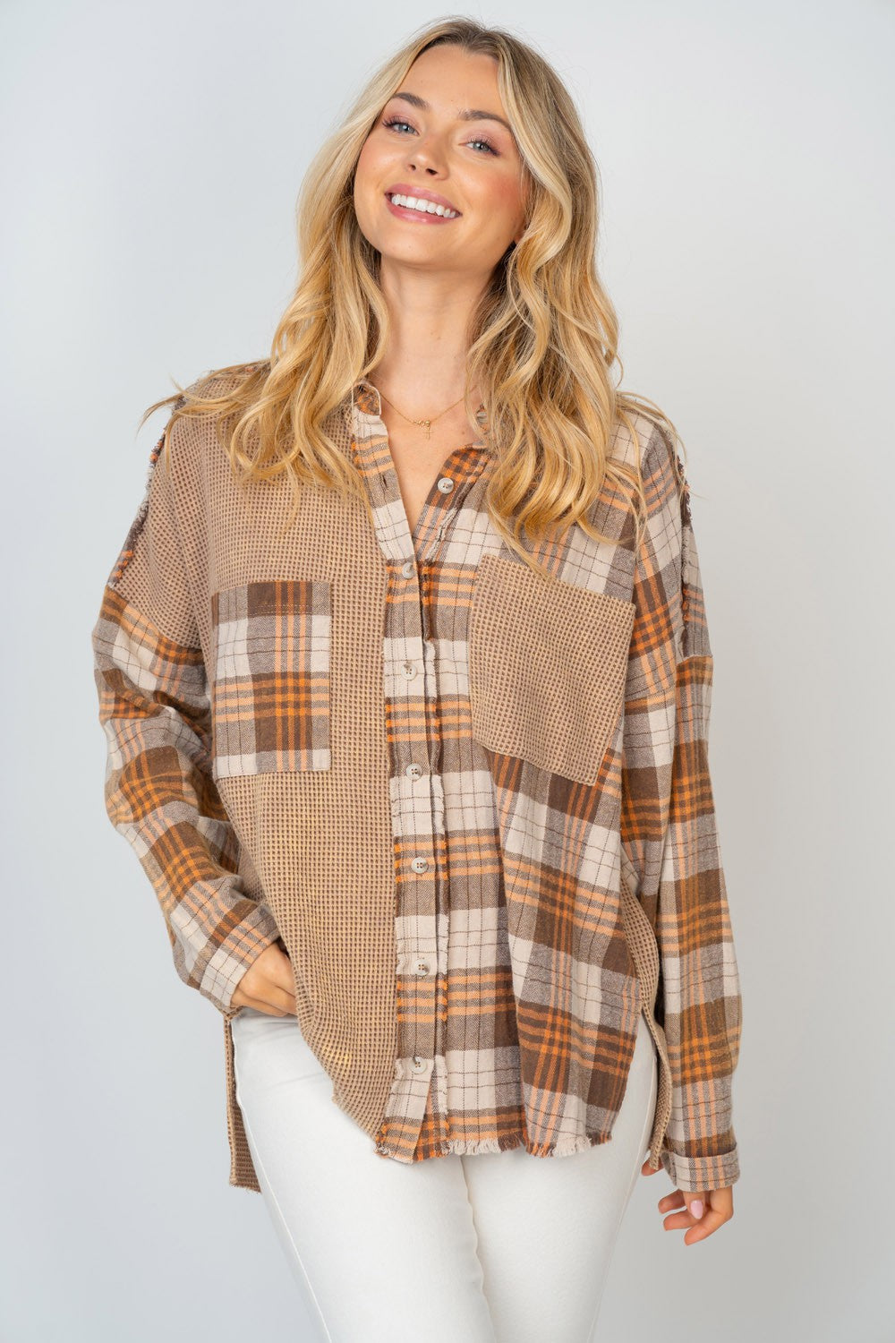 A person with long, blonde hair smiles while wearing the White Birch Full Size Contrast Plaid Button Down Shirt in beige, brown, and white hues, paired with white pants.