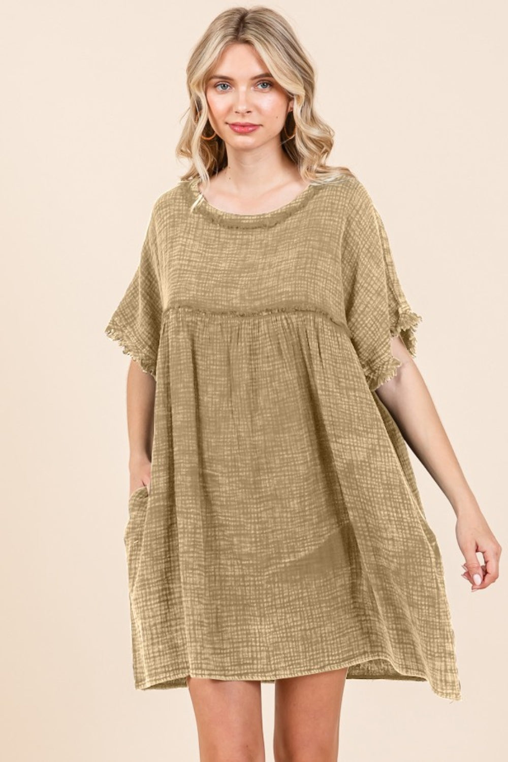 A person is wearing the Culture Code Full Size Short Sleeve Babydoll Texture Dress with Pockets, characterized by its loose fit and short sleeves, in a light brown shade, while standing against a plain background.