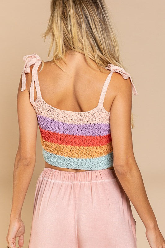 A person is wearing a colorful, rainbow-striped Tie-shoulder Sweater Crop Tank Top paired with light pink pants against a plain background.