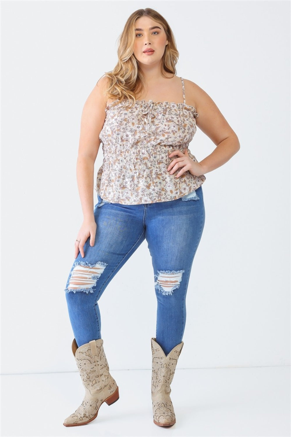 A person with long hair, wearing the Zenobia Plus Size Frill Floral Square Neck Cami and dark jeans, stands with one hand on their hip and the other relaxed by their side.