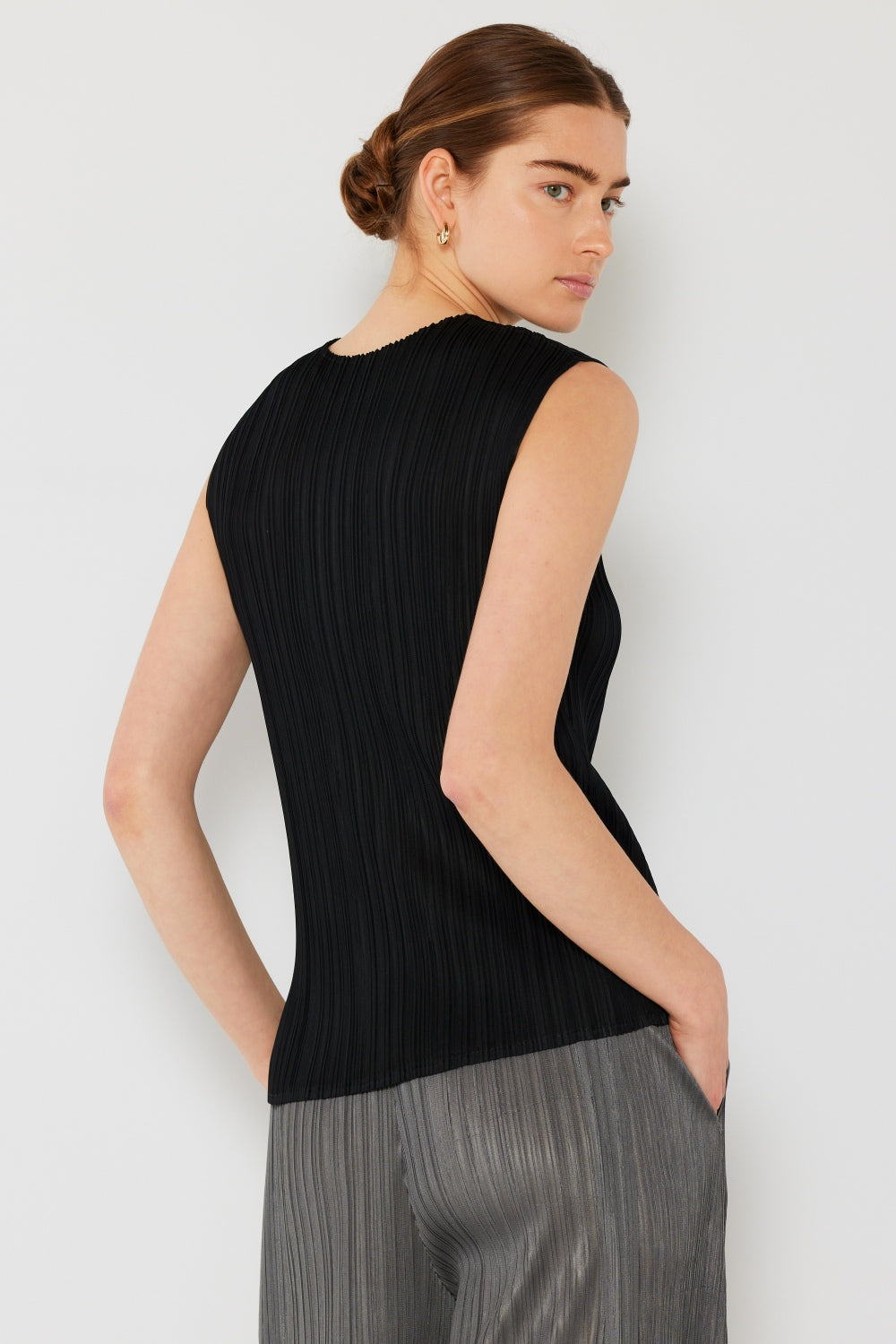 Person wearing a Marina West Swim Pleated Sleeveless Crewneck Tank and a gray pleated skirt, standing against a white background.