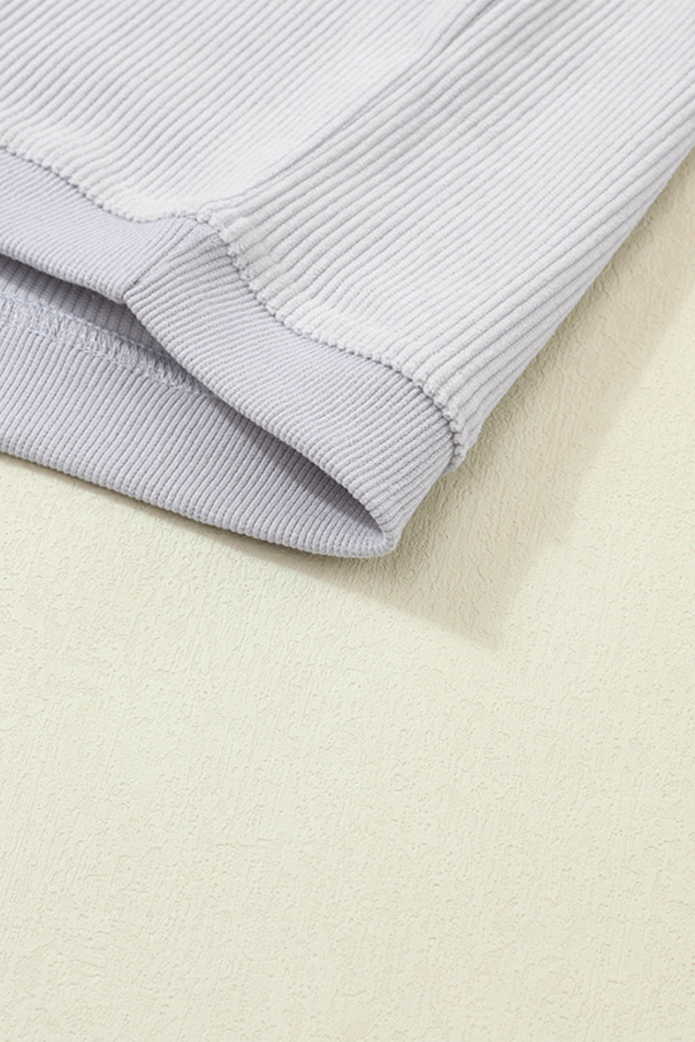 A woman wearing the Light Grey Ribbed Corduroy Oversized Sweatshirt with loose long sleeves, designed in corded fabric, making it fashionable for all body shapes.