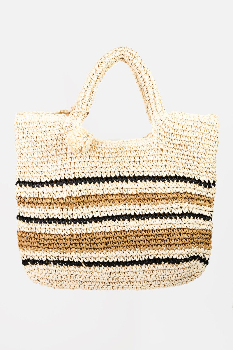 A person wearing a brown hat, white top, and black pants carries the stylish Fame Striped Straw Braided Tote Bag.