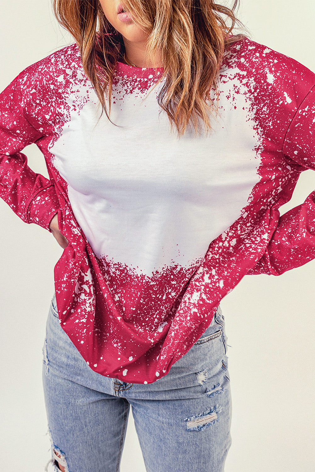 A person with long hair is facing away, wearing a casual Fiery Red Tie-dyed Crew Neck Pullover Sweatshirt and light blue distressed jeans.