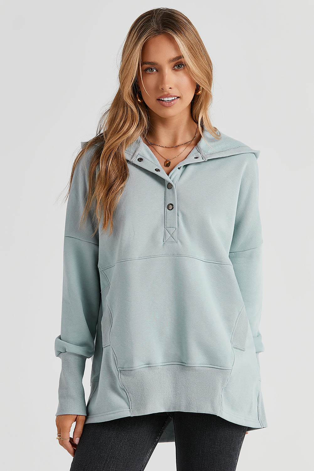 A person with long hair is smiling and looking over their shoulder while wearing a Gray Batwing Sleeve Pocketed Henley Hoodie.