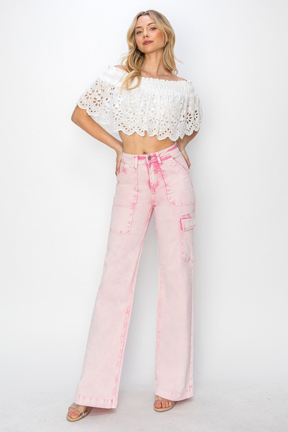 Person wearing the RISEN Full Size High Rise Wide Leg Cargo Pocket Jeans in light pink, featuring front pockets and a button-zip closure, standing against a white background.