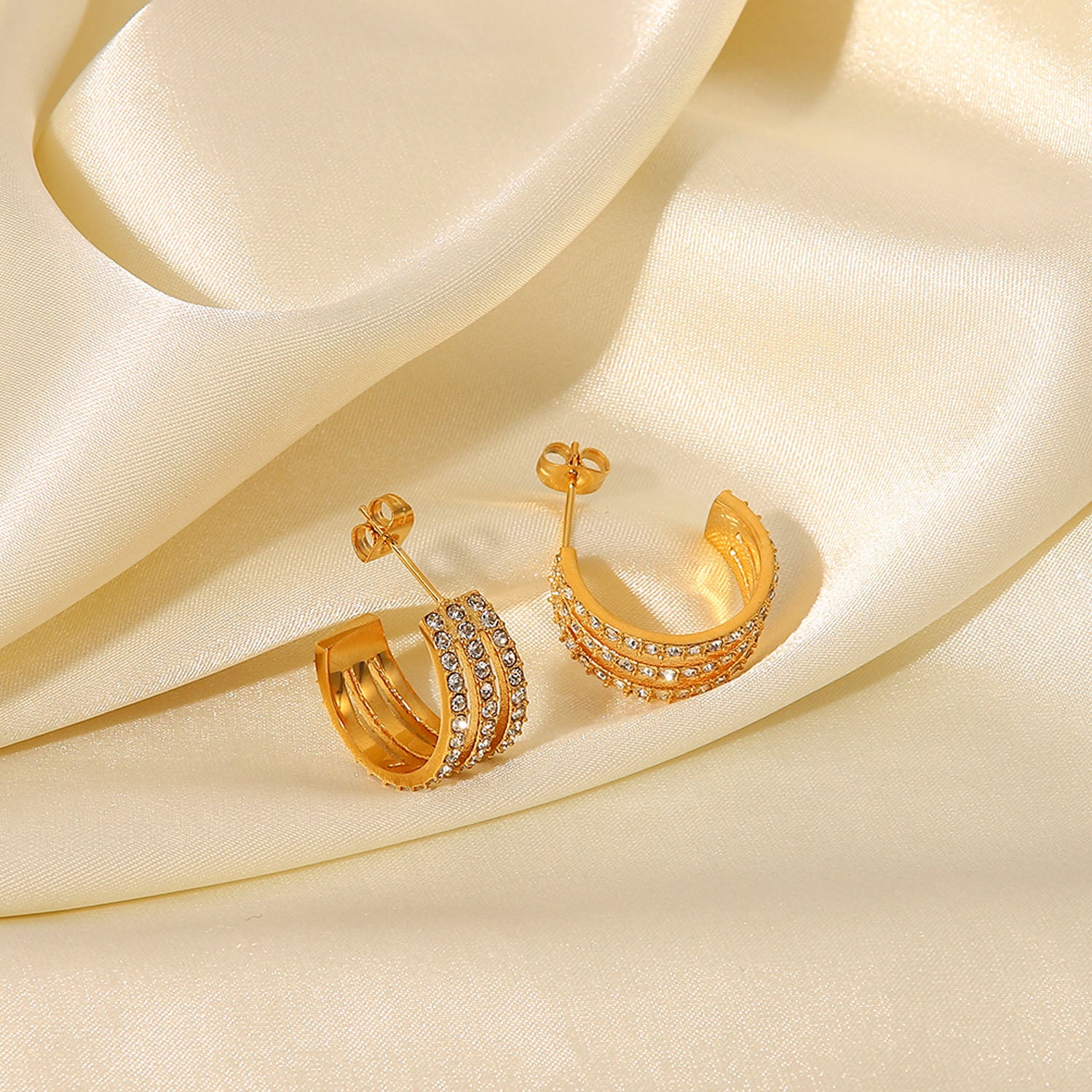 The Stainless Steel Inlaid Zircon C-Hoop Earrings perfectly blend elegance, featuring a triple row of small, clear gemstones on each gold-plated hoop.