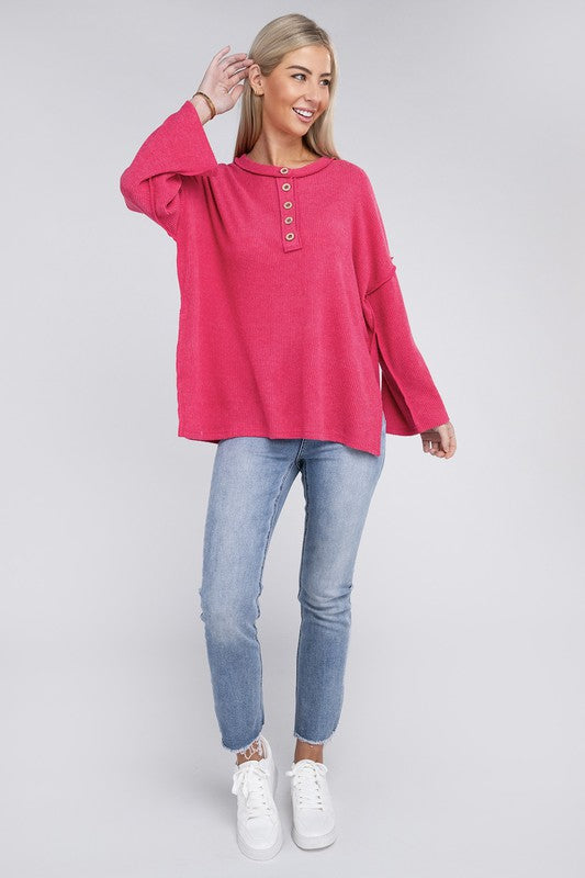 Woman in a blue Ribbed Brushed Melange Hacci Henley sweater with button details posing with her hand on her chin.