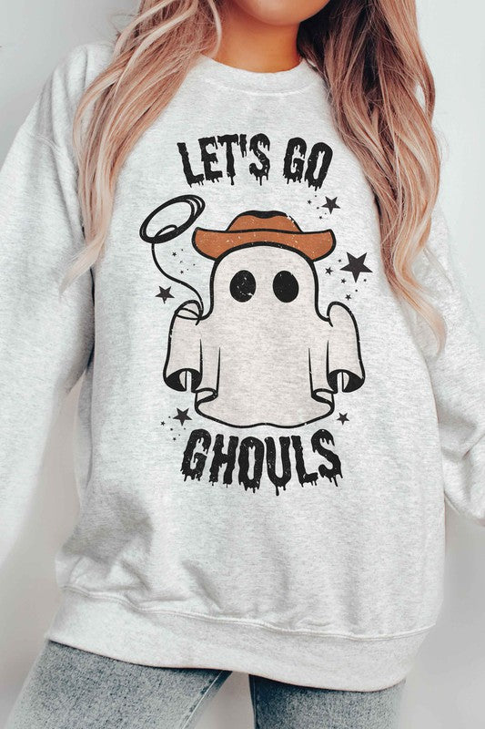 Individual adorned in a LETS GO GHOULS Graphic Crewneck, characterized by a beige hue and featuring a ghost donning a cowboy hat along with the text "Let's Go Ghouls.