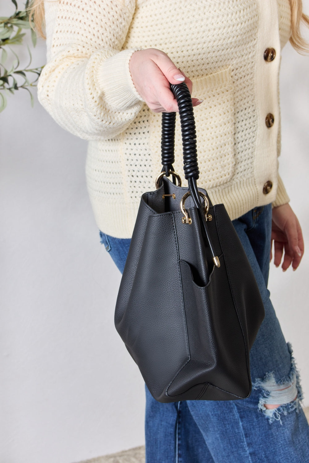 Effortlessly displaying the SHOMICO Faux Leather Handbag with Pouch, which features a spacious design in brown with gold accents and a woven handle, this piece exemplifies versatility. Paired with a cream sweater and blue jeans, its minimalist style perfectly balances fashion and function.