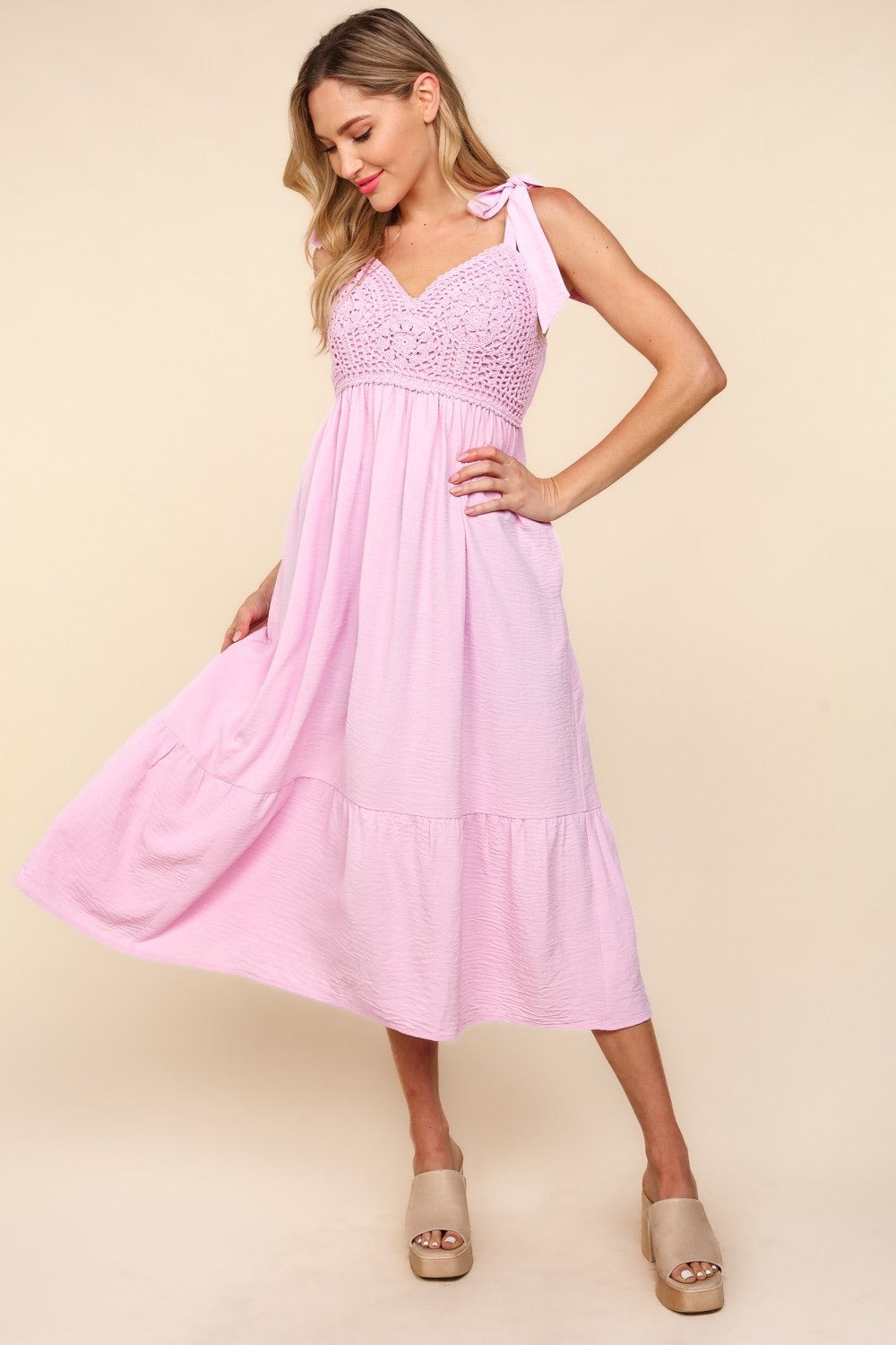 A woman in the Haptics Crochet Lace Ruffle Hem Cami Midi Dress poses against a beige background. She wears neutral-colored platform sandals.