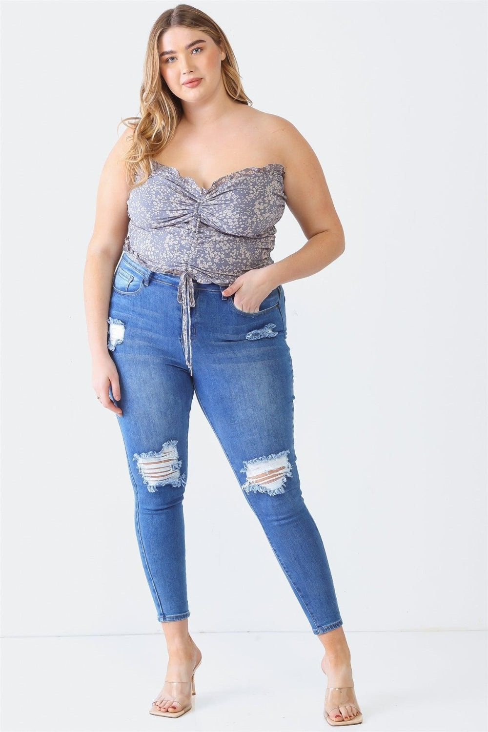 A person with long hair is wearing the Zenobia Plus Size Drawstring Smocked Floral Tube Top paired with ripped jeans, standing against a plain background—a perfect addition to any summer wardrobe.