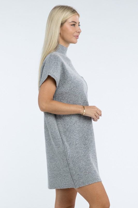 A woman stands wearing a brown Mock Neck Short Sleeve Sweater Dress with a pocket on the left side of the chest, paired with black ankle boots. She is posing against a plain white background.