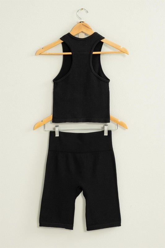 The Power Move Cropped Tank Top and Biker Shorts Set hangs on a wooden hanger against a white background, making it the perfect workout apparel.