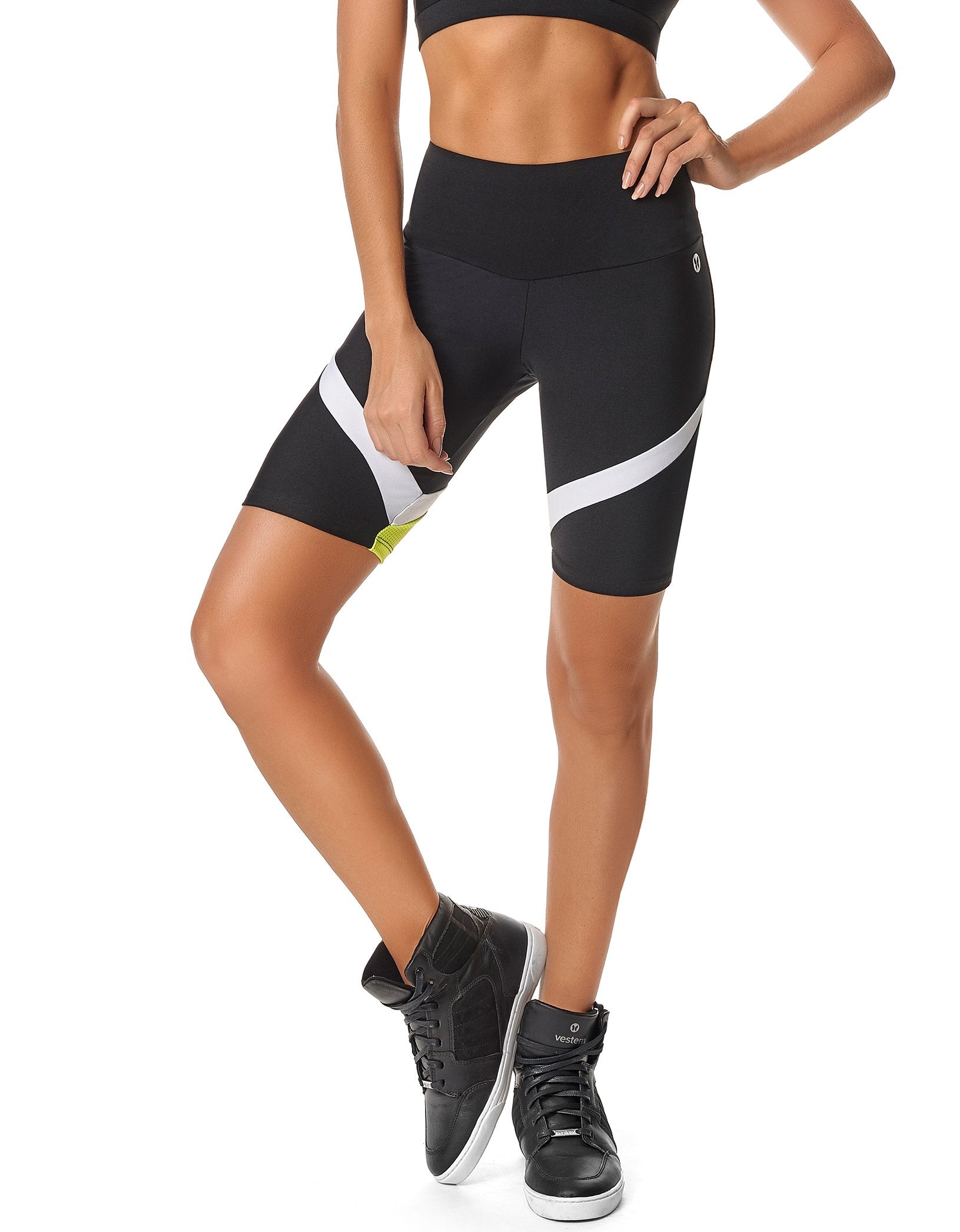 A person in a black sports bra and Calle Ocho Women Biker Shorts with white stripes, made from sweat-wicking fabric for ultimate comfort, poses with one hand on their hip. They sport black high-top athletic shoes, ideal for any fitness activity.