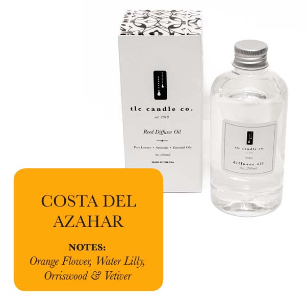 A clear glass bottle of "Refill Oil - Costa Del Azahar" by TLC Candle Co. is paired with a sleek white box. The label features "Costa Del Azahar," revealing aromatic notes of orange blossom, water lily, orriswood, and vetiver that capture the essence of a coastal breeze with every inhalation.