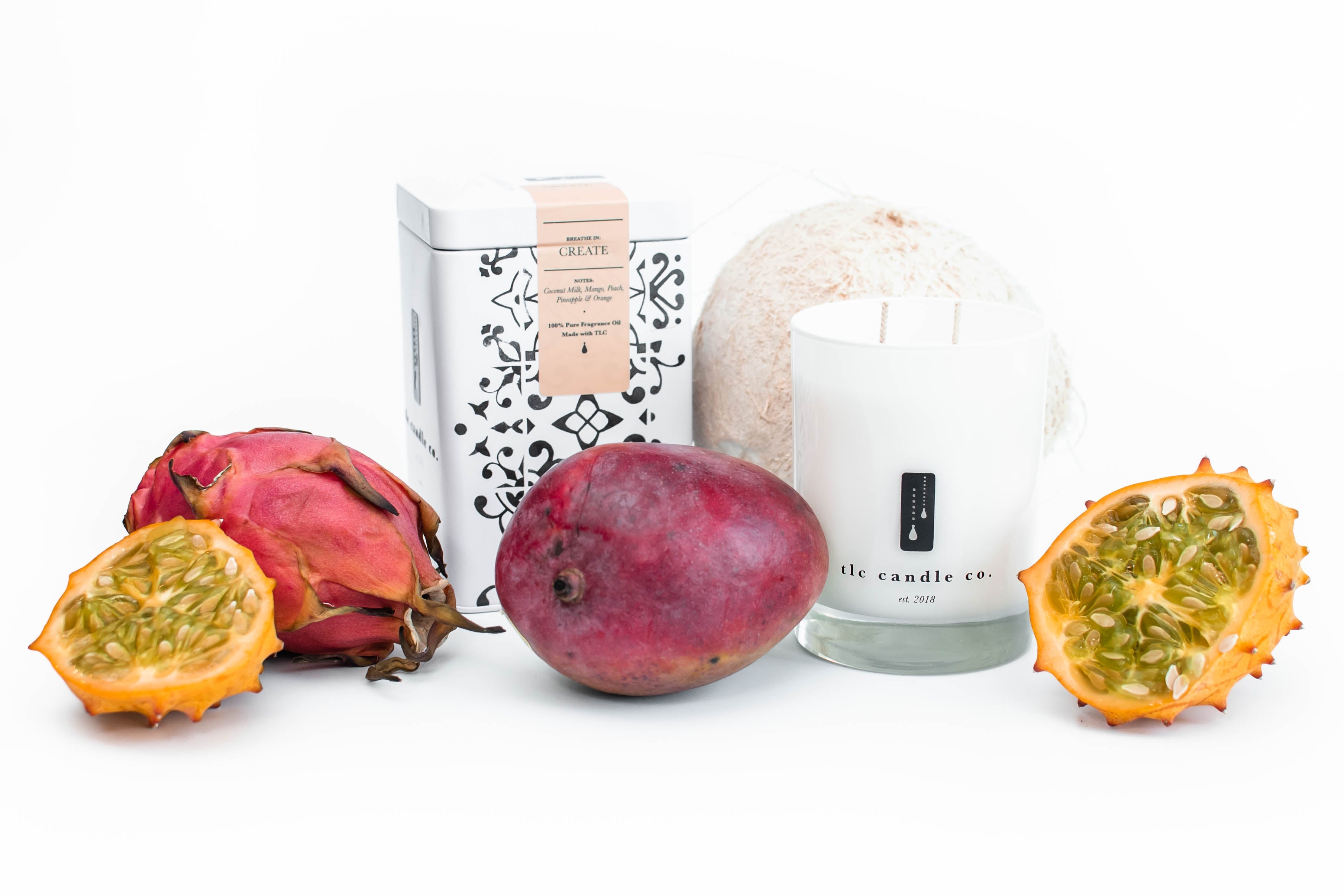 A display featuring the Create - Coconut and Tropical Fruits Soy Candle and a tea tin, all set against a white background.