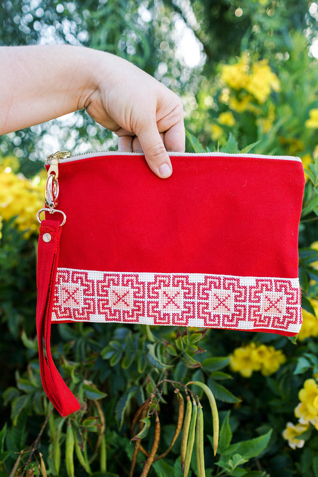 The Safa Tatreez Pouch - Red showcases exquisite Palestinian tatreez with intricate geometric patterns along the bottom edge. Hand-embroidered with care, it supports fair trade practices.