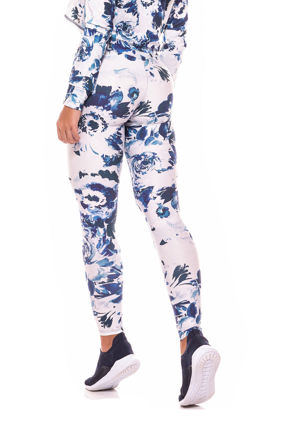 Wearing the Trust Drawstring Legging in a matching blue and white floral design with tummy control, a person poses near a white chair on a wooden floor indoors.
