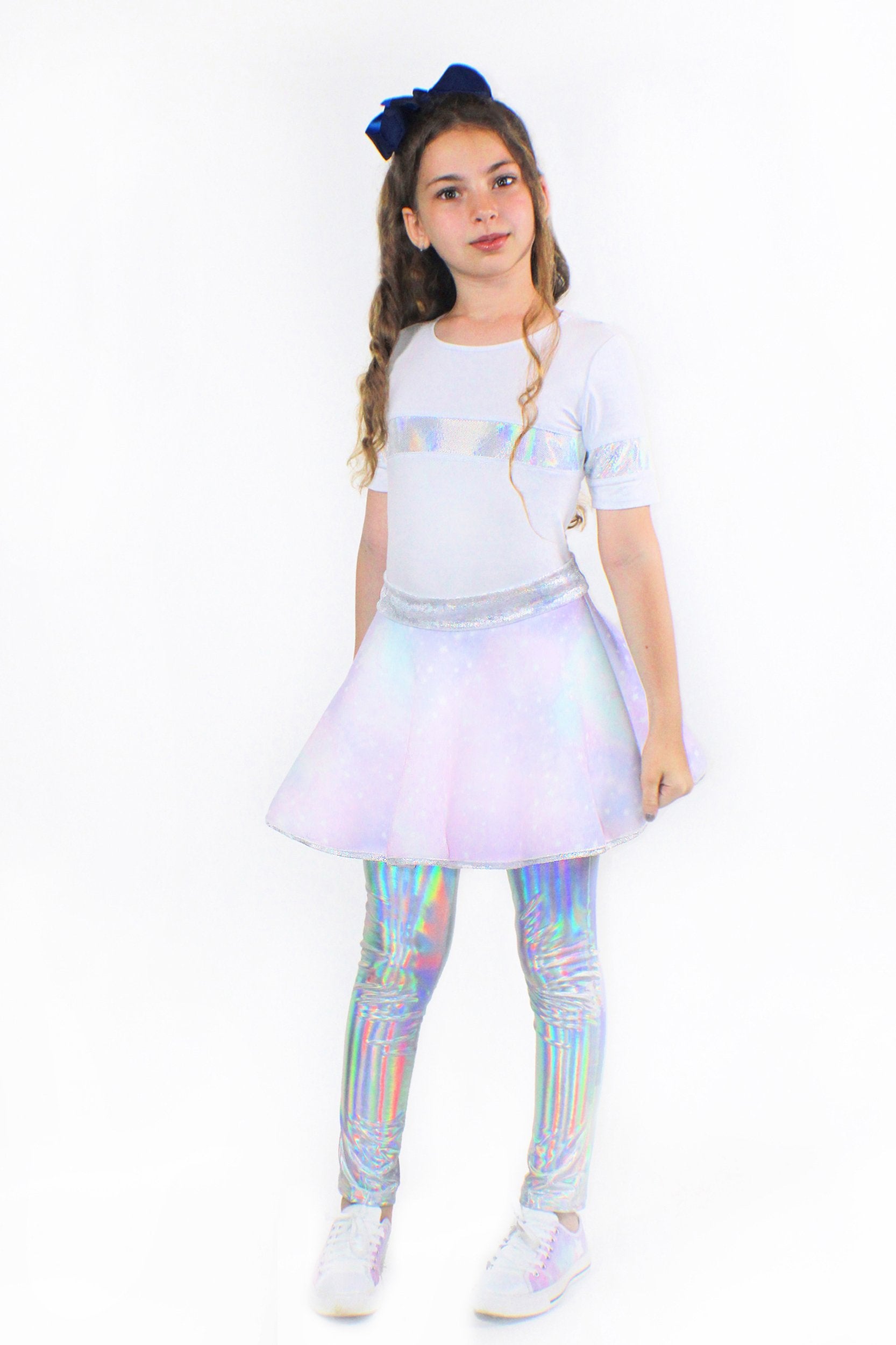 A young girl wearing a white t-shirt and a Sky Blue Beech Lana Galaxy holographic skirt.