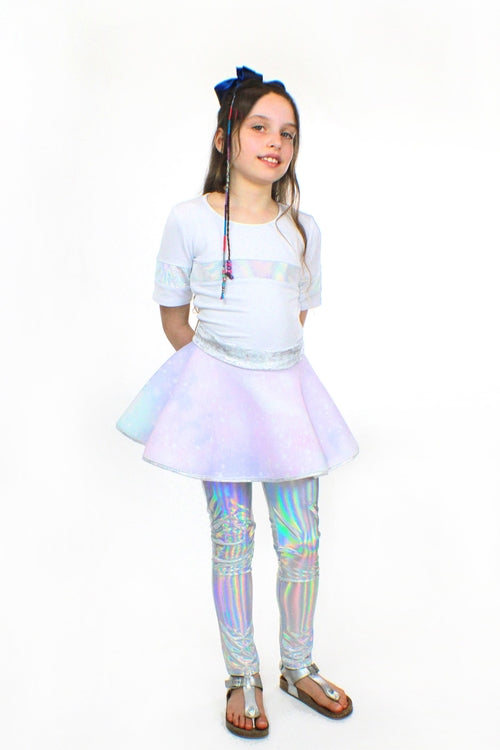 A young girl wearing a white t-shirt and a Sky Blue Beech Lana Galaxy holographic skirt.